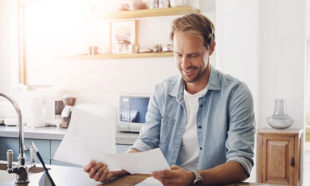 Man smiling at bills after applying for Best Debt Consolidation Loans
