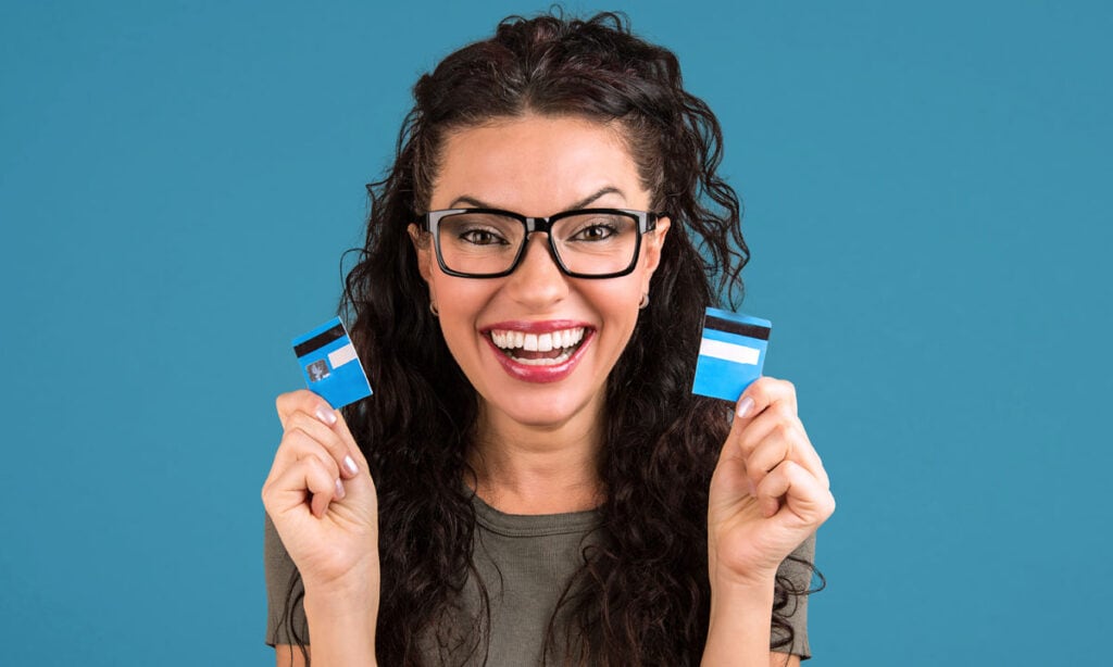 Woman with long black hair holding a credit card that is cut in half because she has learned how to consolidate loans and credit cards.