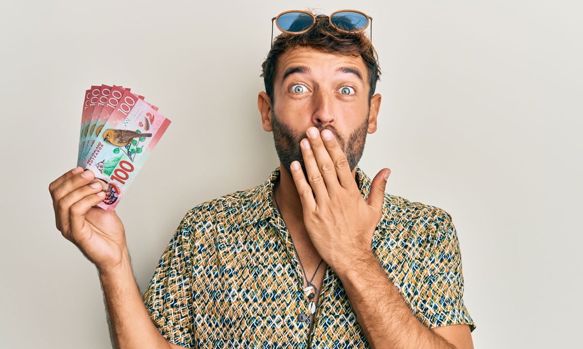 Man holding cash with a surprised expression and hand over his mouth, illustrating how to get money fast with Loan Direct's same-day loans